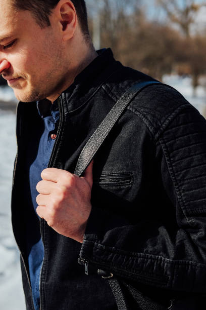 istock Young man in black denim jacket and leather backpack walking. Selective focus. 939848828