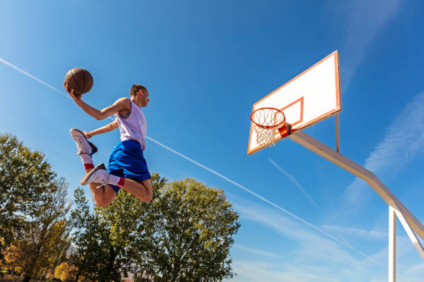 istock Young Basketball street player making slam dunk 939851474