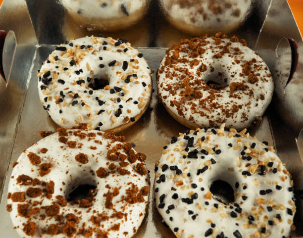 istock White donut with sprinkles isolated on golden background 939856192