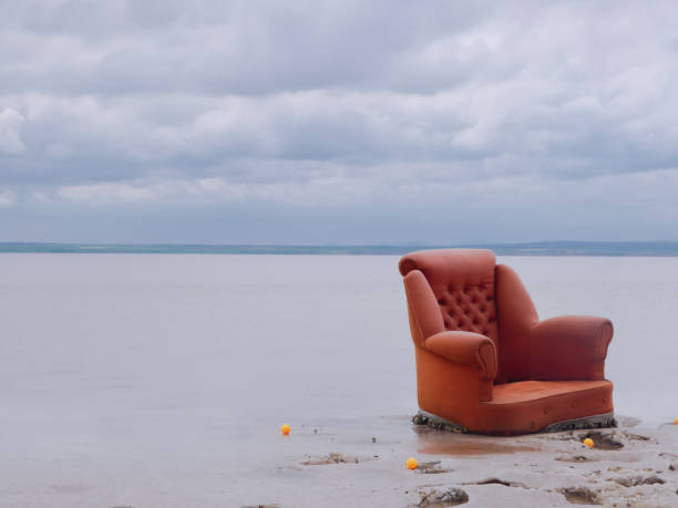 istock Orange color sofa on the beach under cloudy sky 939858494