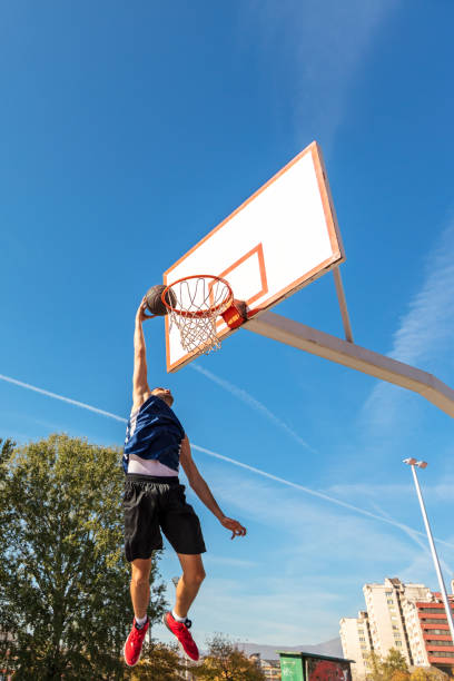 istock Young Basketball street player making slam dunk 939858676