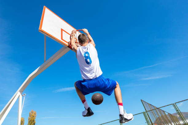 istock Young Basketball street player making slam dunk 939858716