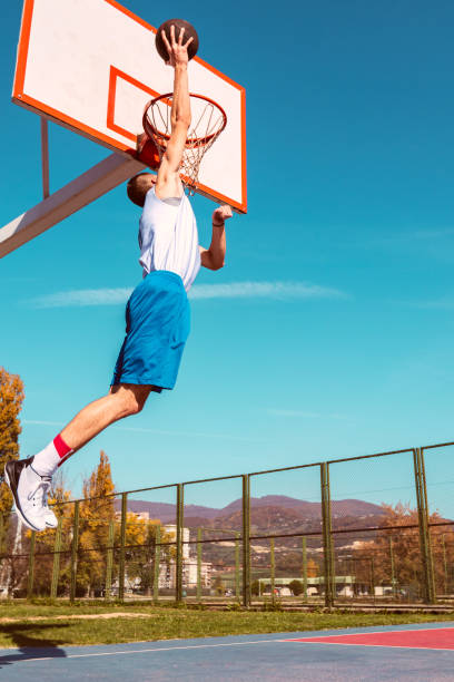istock Young Basketball street player making slam dunk 939858836
