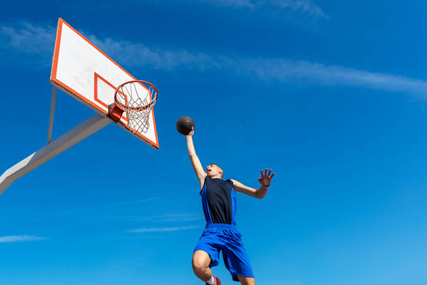 istock Young Basketball street player making slam dunk 939859214