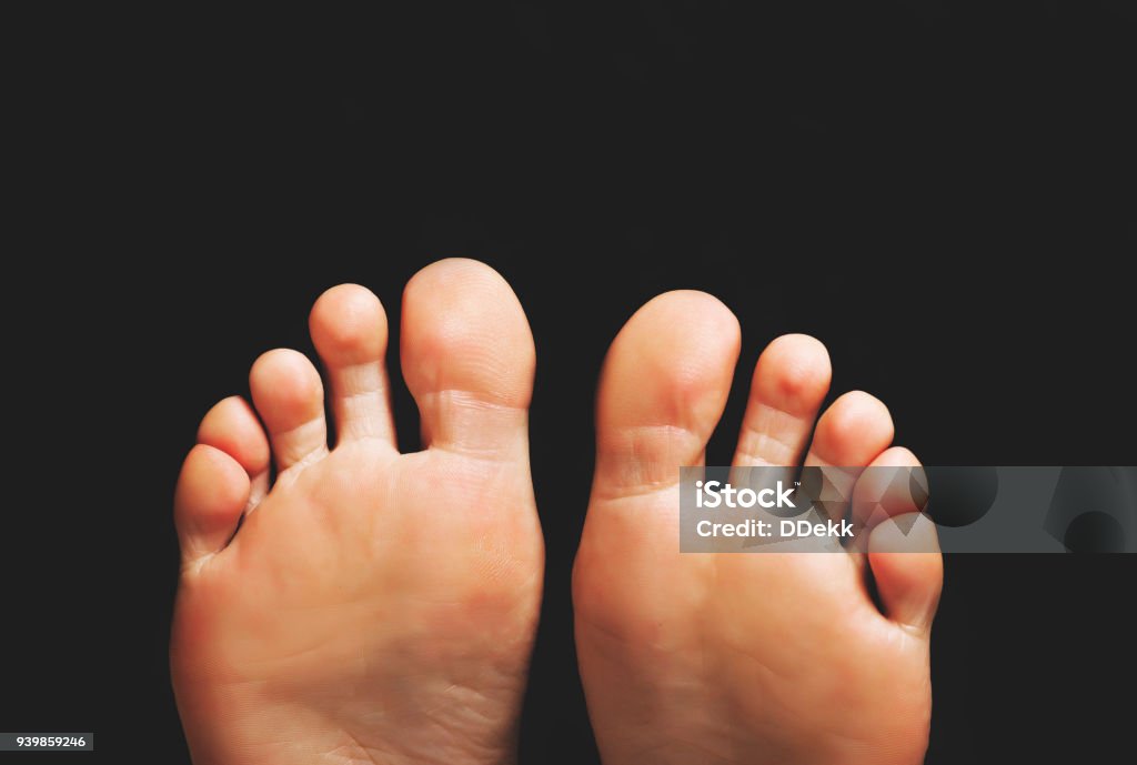 female clean heels on a black background Foot Stock Photo