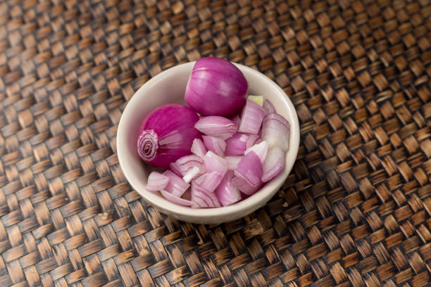 istock Red Onions peeled and Chopped red onion isolated in a cup white. 939866568
