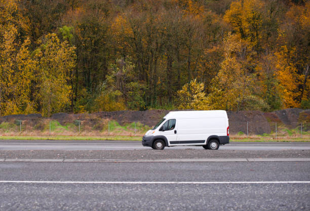 carico commerciale e mini van per piccole imprese in viaggio con alberi gialli autunnali sullo sfondo - middle of the road immagine foto e immagini stock