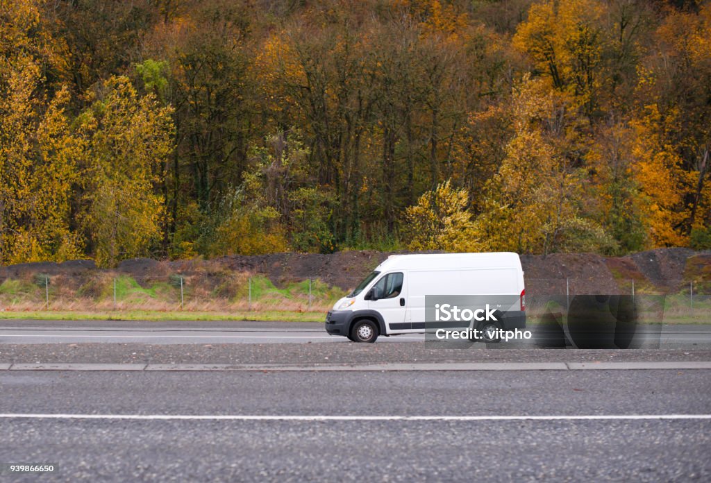 Commercial cargo and small business mini van going on the road with autumn yellow trees on the background Commercial compact cargo mini van vehicle for small business going on the entrance to interstate road with autumn yellow gold trees on the background Mini Van Stock Photo