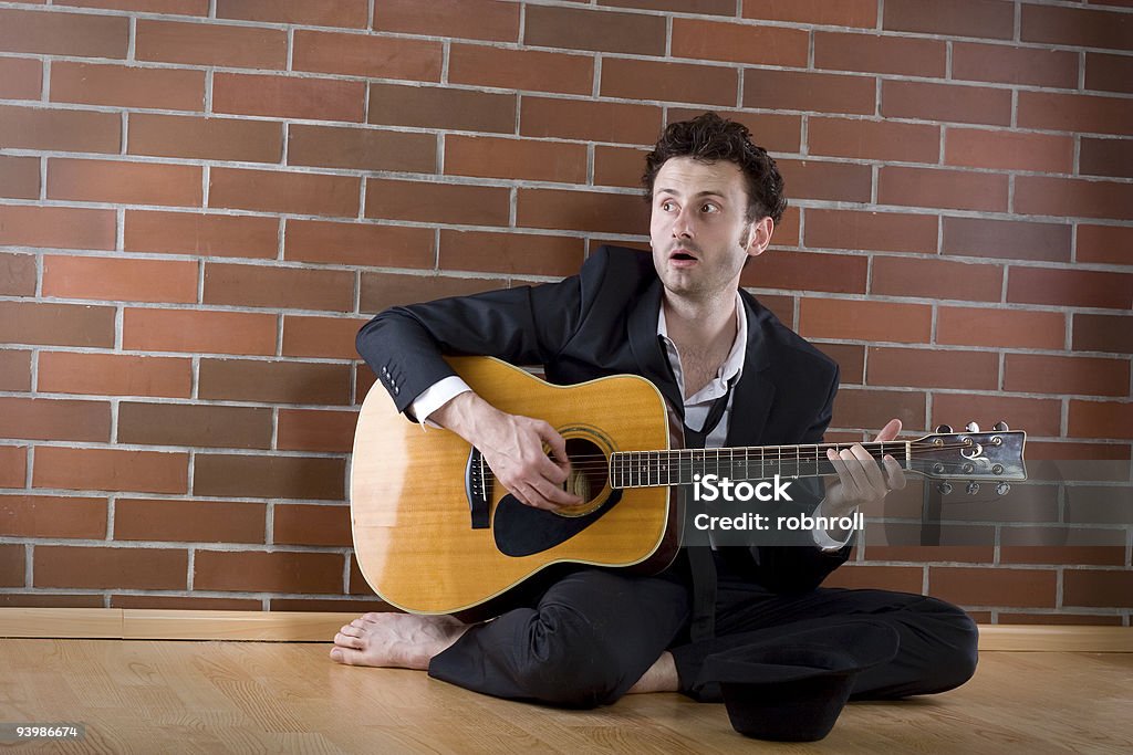 Geschäftsmann sitzt mit einer Gitarre auf dem Boden und singt - Lizenzfrei Armut Stock-Foto