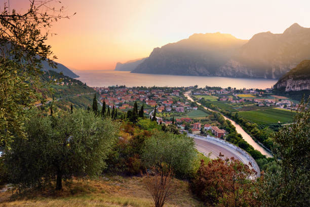 Scenic aerial view of Riva del Garda town, located on a shore of Garda lake, surrounded by beautiful rocky mountains Scenic aerial view of Riva del Garda town, located on a shore of Garda lake, surrounded by beautiful rocky mountains. Spectacular autumn sunset. lake garda photos stock pictures, royalty-free photos & images