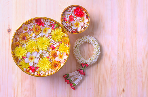 Colorful flower in water bowls decorating on wood background for Songkran Festival or Thai New Year.
