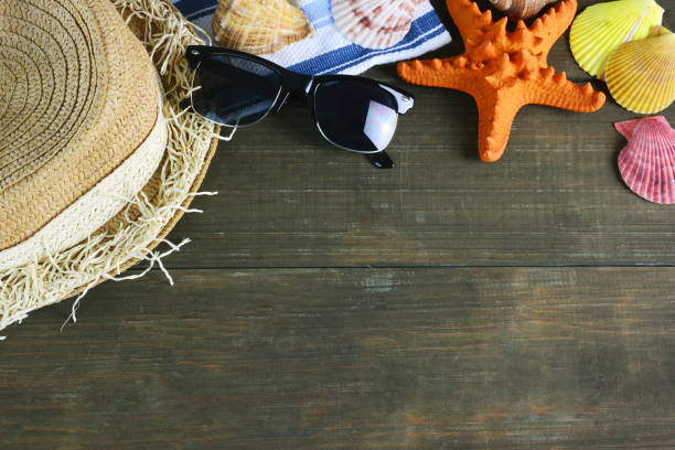 istock Hat, sunglasses and seashell on wooden summer background. 939887172