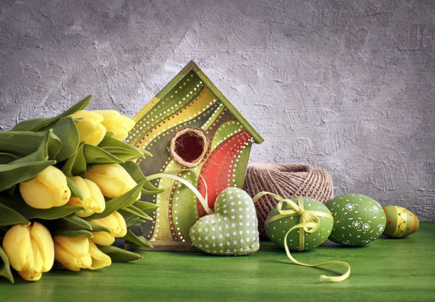 istock Yellow tulips, birdhouse and painted Easter eggs with stuffed heart, Spring decorations 939892190
