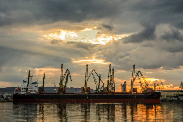 istock Boat waiting to be loaded with Cranes at sunset. 939911660