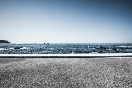 scenic view of seascape against sky,empty tarmac road on foreground.
