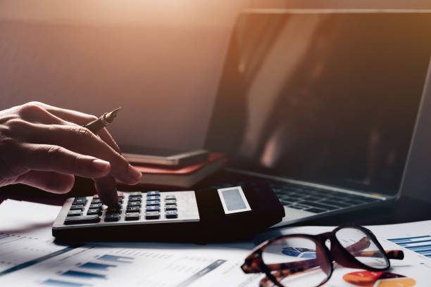 Business accounting, Business man using calculator with computer laptop, budget and loan paper in office. stock photo