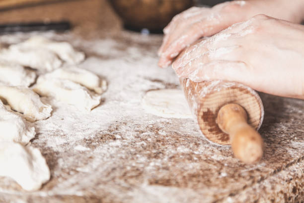 istock Female hands roll out dough with wooden rolling pin 939929950