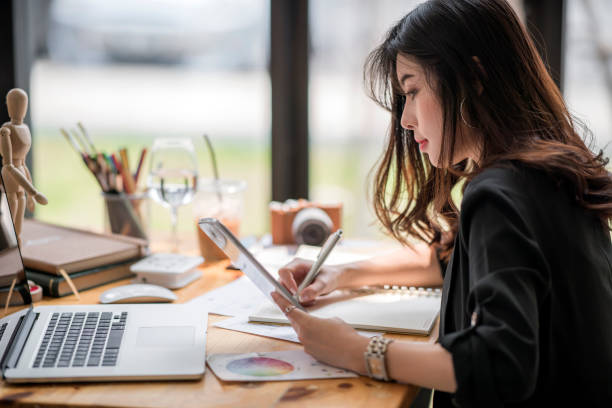female designer working with paperwork  and looking at tablet screen