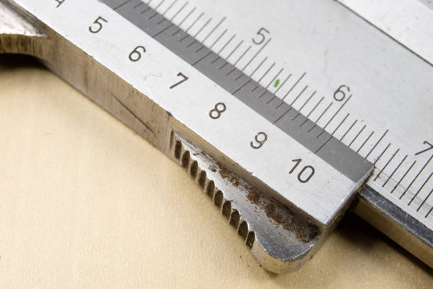 Measuring tools in the workshop. Caliper for locksmith work on a wooden table. Dark background.