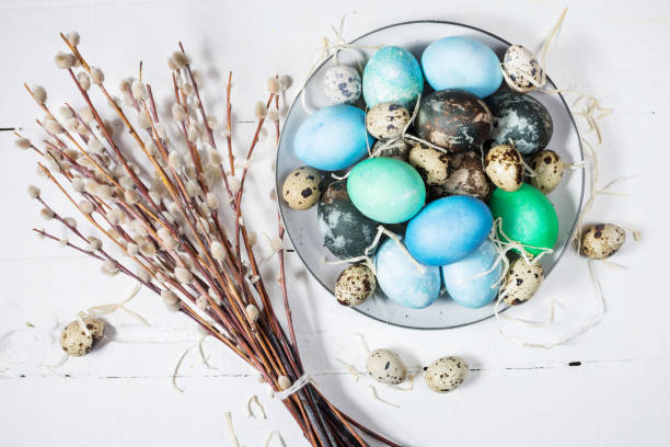 istock painted eggs on plate, quail and chicken eggs, paint and brush on white wood background, Easter decorations 939938466