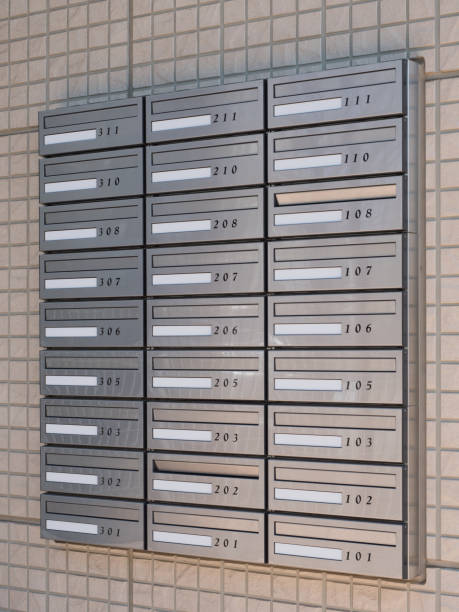 Several gray wall-mounted mailboxes line a hallway, each marked with a unique number for different apartments. The setting appears modern and organized.