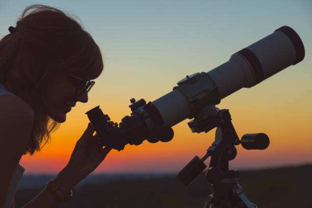istock Young woman looking at the sky with astronomical telescope. 939943916