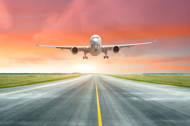 istock Passenger airplane landing on a runway in the evening during a bright red sunset. 939946542