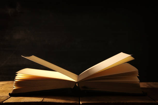 istock image of open antique book over wooden table. 939947756