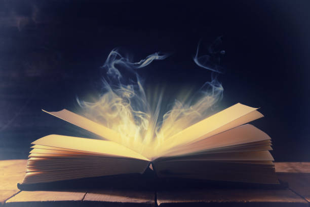 istock image of open antique book over wooden table. 939947786