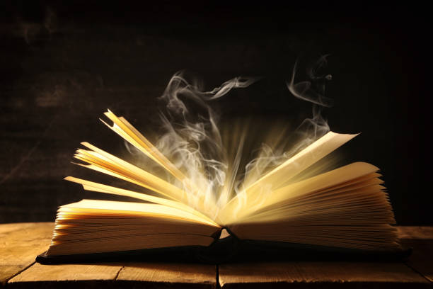 istock image of open antique book over wooden table. 939947792