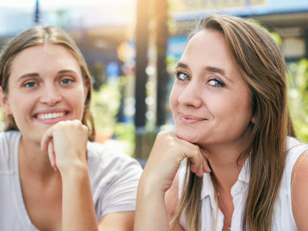 istock Two beautiful blonde girlfriends at sunny sidewalk cafe smile 939951448