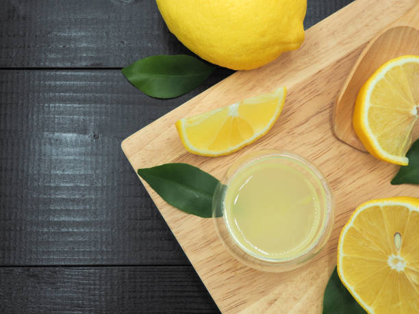 istock Fresh lemon juice in small bowl and lemon slice on dark wood background 939956538