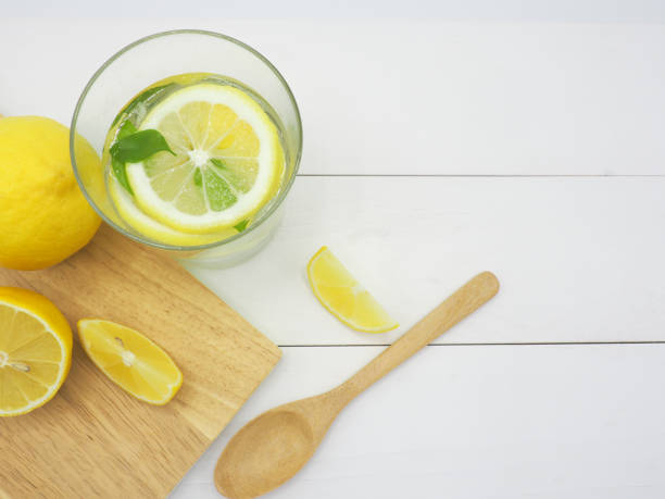 istock Fresh lemon in water and lemon slice on white wood background 939956844