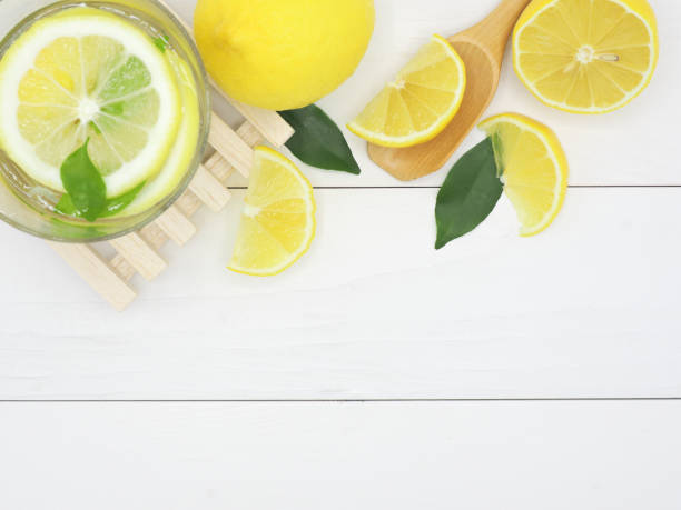 istock Fresh lemon in water and lemon slice on white wood background 939956862
