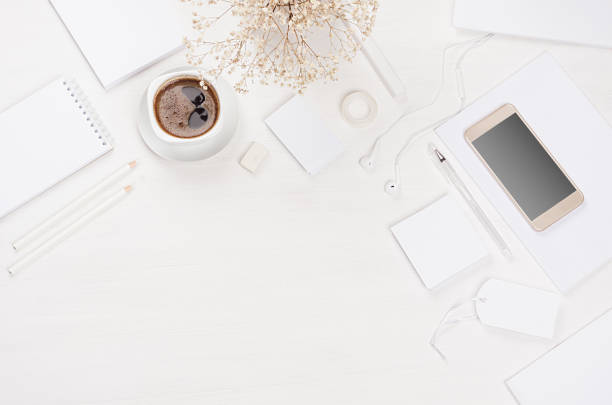 istock Elegant gentle soft white working place with white stationery, border, phone, coffee on white wooden board. Modern fashion simple work place. 939958538