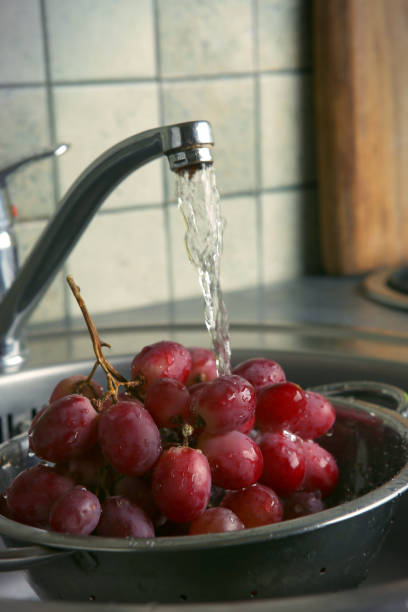 istock Washing fresh grapes in colander under the tap. 939997672