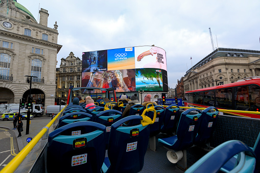London, UK - Feb 22, 2018: Tourists enjoying the ride on an open-air double decker Tour Bus in London.