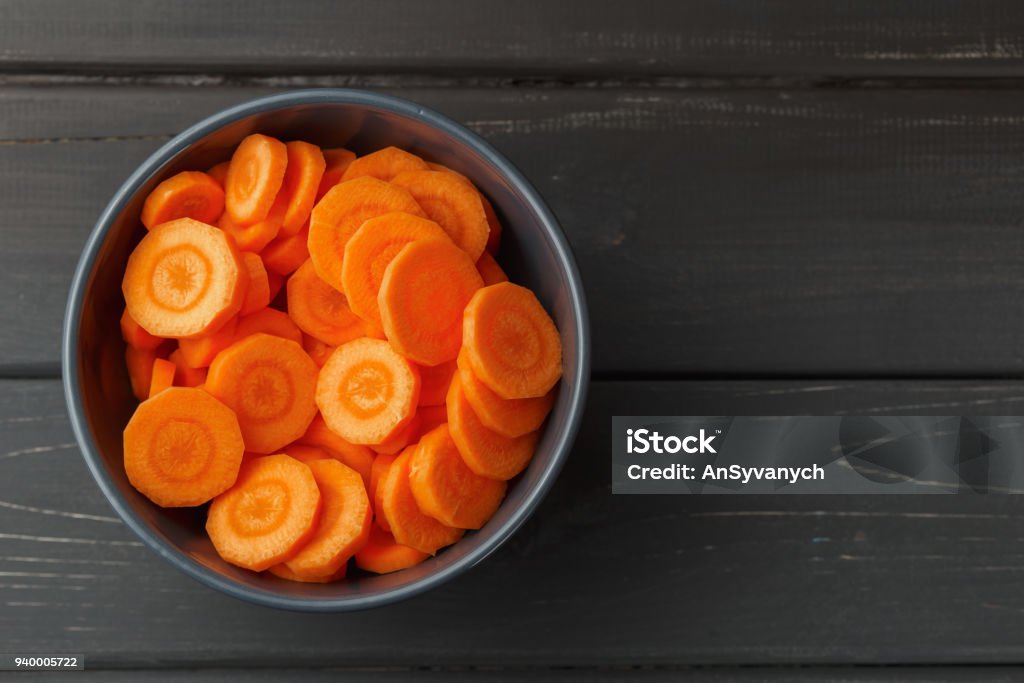 Sliced carrots in a bowl on black background Sliced carrots in a bowl on black wooden background. Top view Carrot Stock Photo