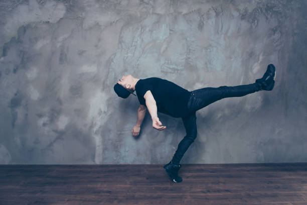 istock Freedom! A guy is doing a dance move which looks like he is going to float in the air. Dancer is in the black outfit and cap, relaxed 940005962