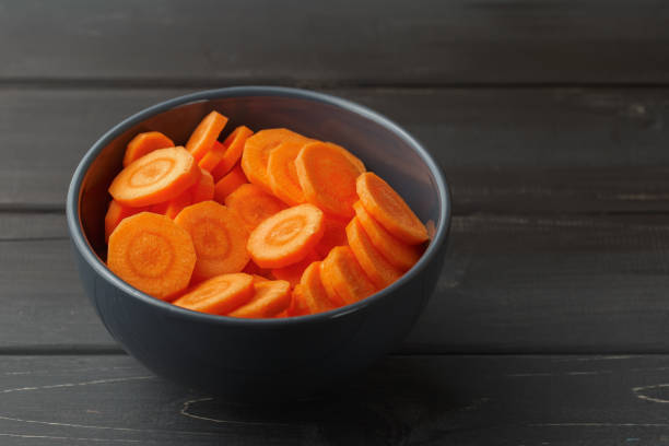istock Sliced carrots in a bowl on black background 940006260