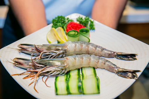 Chef showing fresh raw prawn on plate