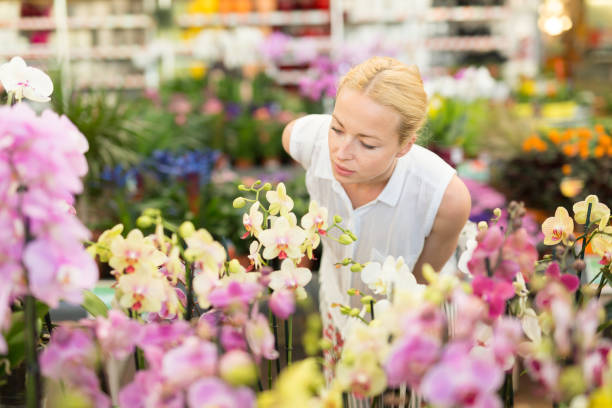 istock Beautiful lady smelling colorful blooming orchids. 940015266