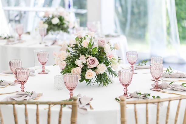 istock Beautiful table setting with crockery and flowers for a party, wedding reception or other festive event. Glassware and cutlery for catered event dinner. 940018216
