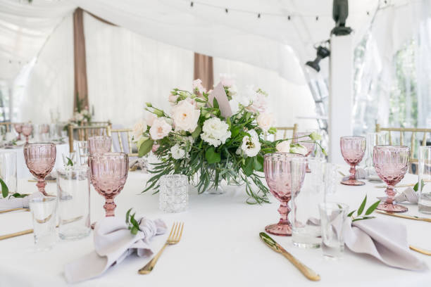 istock Beautiful table setting with crockery and flowers for a party, wedding reception or other festive event. Glassware and cutlery for catered event dinner. 940018276