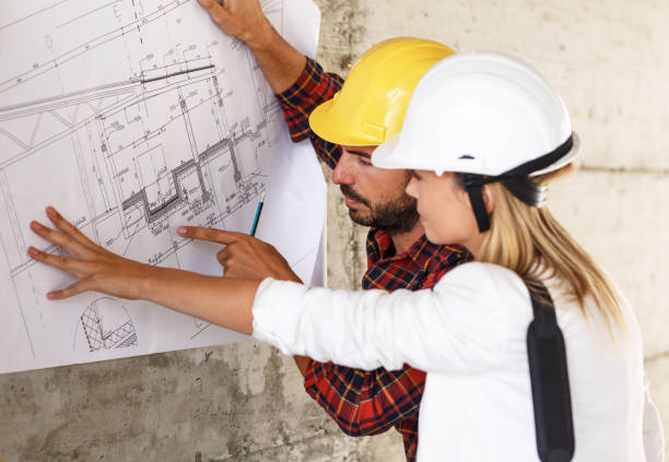 istock Team of inspectors and architects discuss about blueprints on construction site. 940019008
