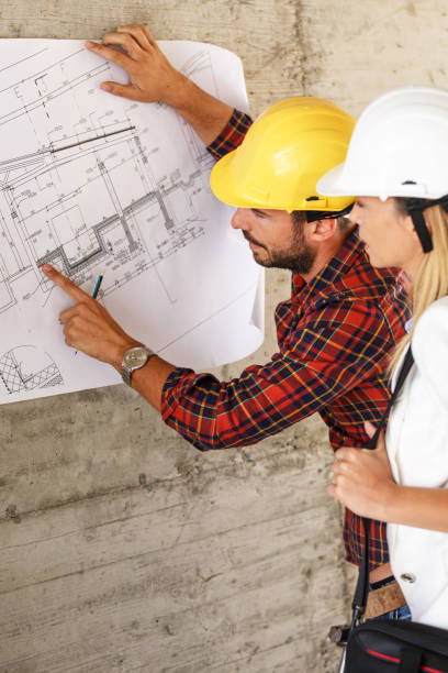 istock Team of inspectors and architects discuss about blueprints on construction site. 940019280