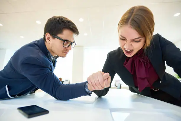 Strong emotional businesswoman showing her leadership position and winning arm wrestling from colleague, competitors concept