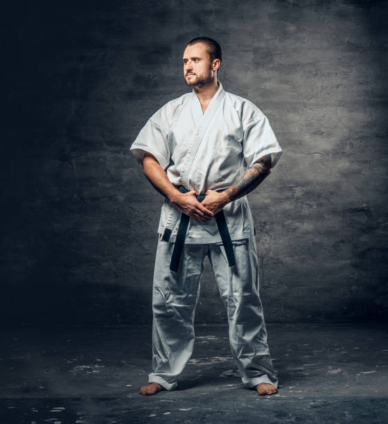 istock Karate fighter dressed in a white kimono over grey background. 940027096