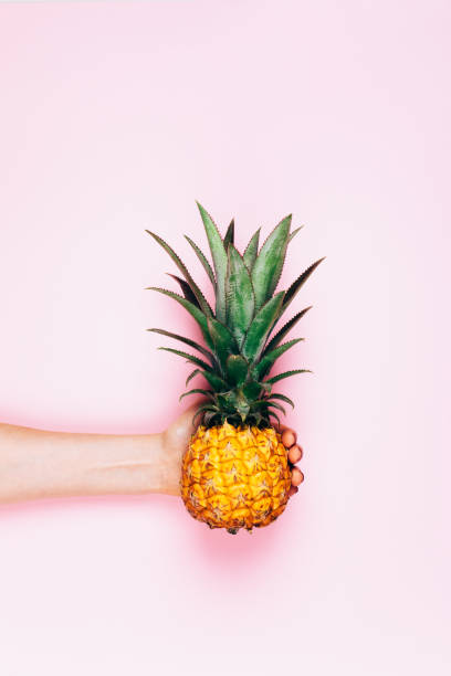 istock Hands with pineapple on stylish pink 940027566