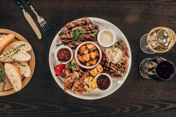istock top view of plate with beef steaks, chicken wings and wine with bread on wooden table 940027770